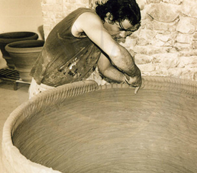 Artigiano tira il colombino per realizzare una grossa conca in terracotta