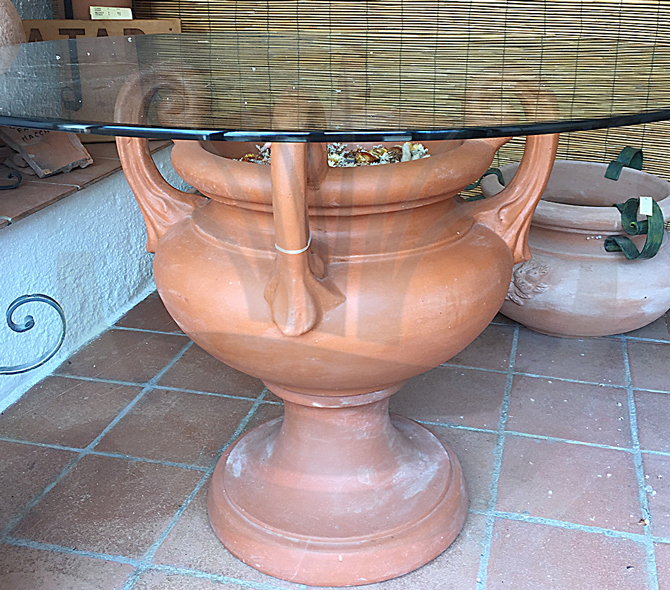 Large smooth urn used as a base for a glass table